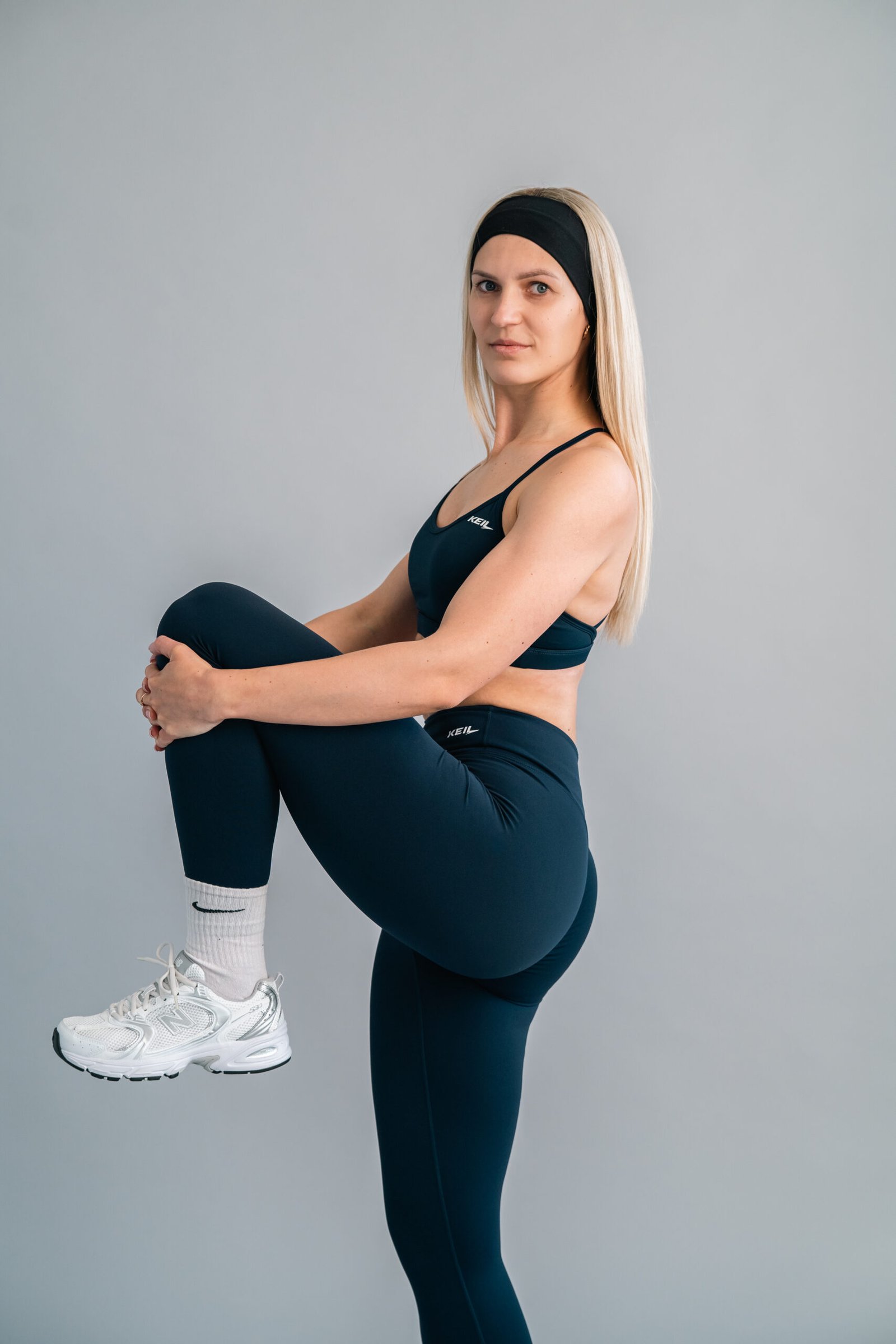 Sieviete trenējas tumši zilos KEIL athletic legingos - fitness, joga un skriešana